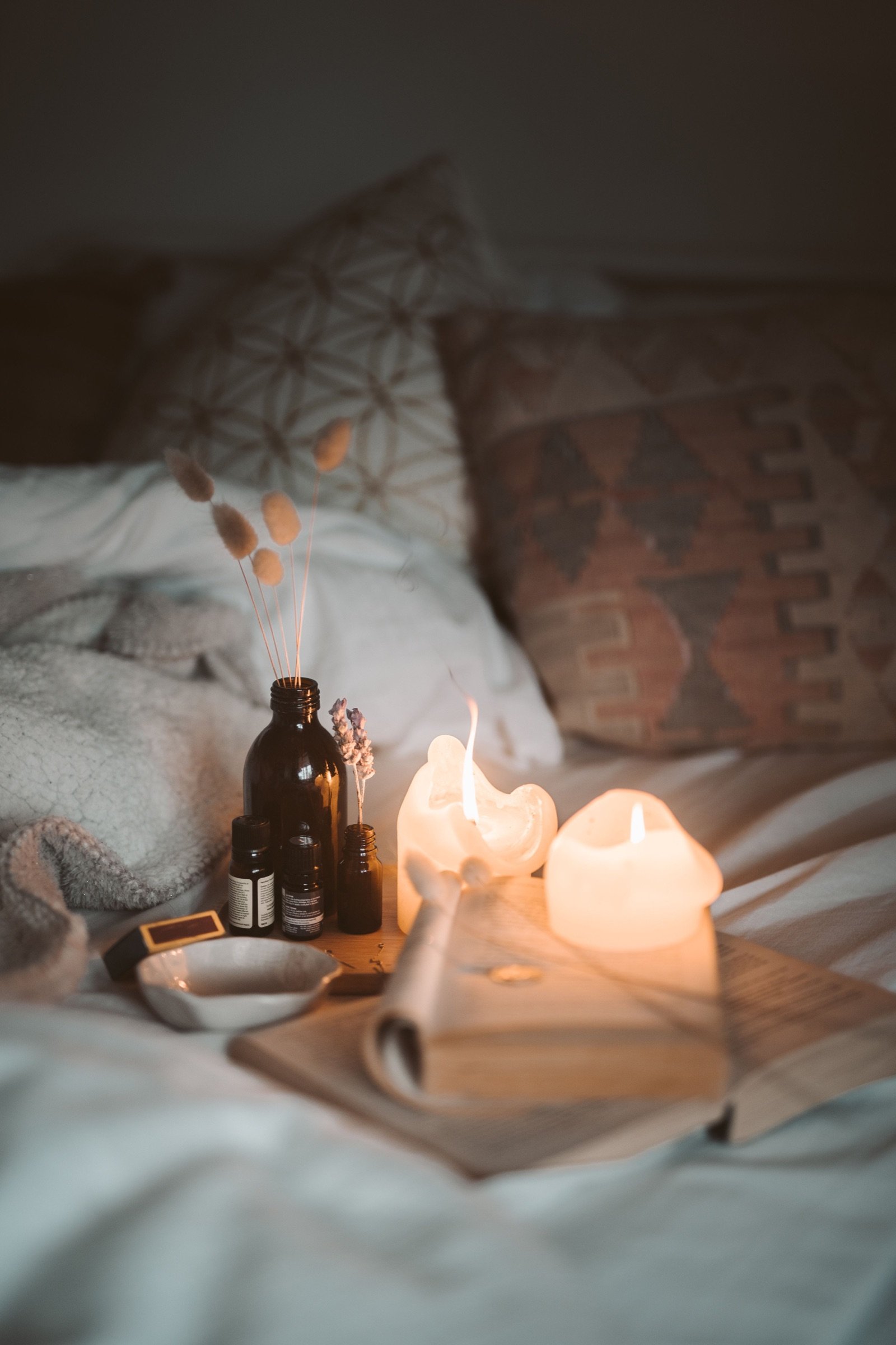 Rituel du soir sur un lit, bougies, livre ouvert et brins de lavande